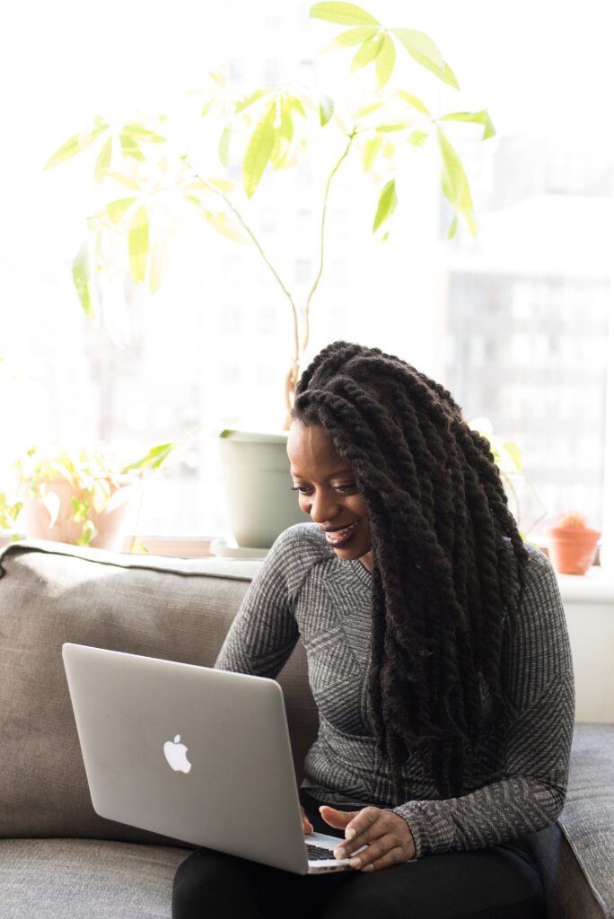 A beautiful african business woman smiles as she receives business support services on her laptop.